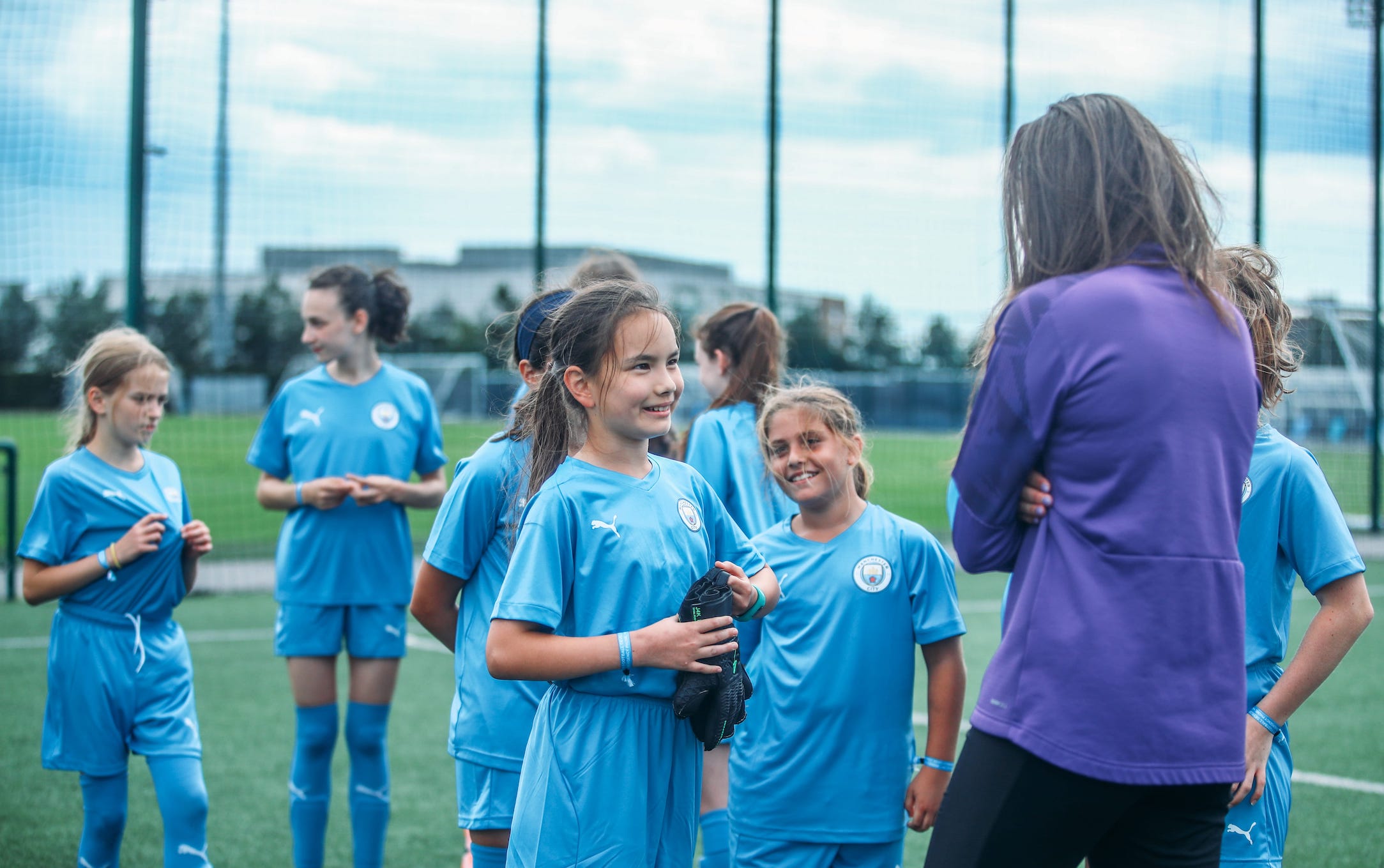Young girls on the Manchester City Football School development programme talking to their coach.